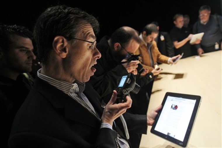 The Apple iPad is examined after its unveiling at the Moscone Center in San Francisco.